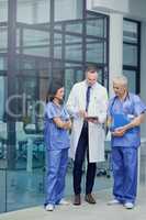 Comparing diagnosis. Shot of a group of doctors talking together over a digital tablet while standing in a hospital.