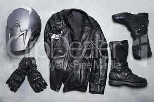 The lifestyle of a rider. High angle shot of biker gear against a gray background.