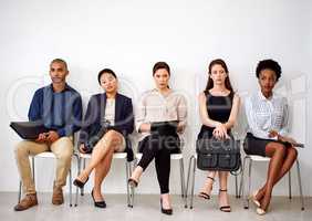 Trying not to let the boredom get to them. Shot of a group of businesspeople seated in line while waiting to be interviewed.