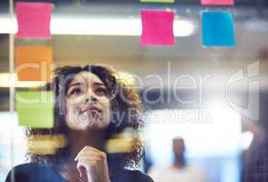 Let your brain be your best friend when problem solving. Shot of a young woman having a brainstorming session with sticky notes at work.