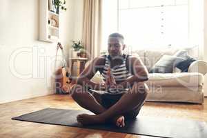 Your thoughts control your life. Shot of a sporty young man meditating at home.