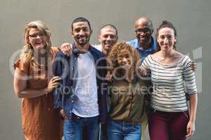 Friends all grouped together. Shot of a group cheerful friends standing together for a portrait while looking at the camera.