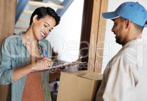 Just sign and the package is yours. Shot of a young woman standing at her front door signing for a package from a courier.