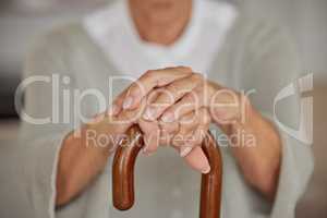 Closeup of a seniors hands, disabled woman holding a cane in a nursing home. An elderly lady needing a walking aid or support, a crutch to lean on after having a stroke at an assisted living facility