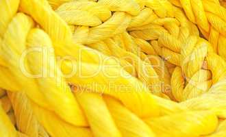 Strong thick braided colorful rope woven and twined. Yellow thick rope macro closeup laying in a heap. Long twisted strong material symbolizes unity, togetherness, and teamwork