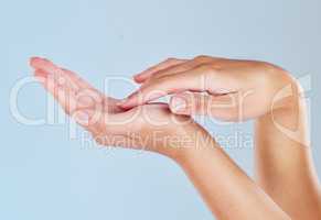 Closeup of female hands touching her palm. One woman with soft, flawless, moisturized skin isolated on a blue background. Elegant fingers showing manicure and hygiene. A skincare and beauty treatment