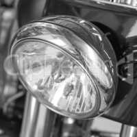 Closeup of a headlight on a motorbike. Motorcycle light with black and white filter. One light bulb on a sliver modern classic chrome coated motor vehicle. Clean, sleek chromium maintenance on a bike