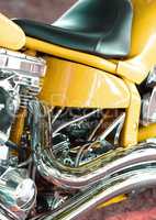 Closeup of a custom design motorbike with chrome leather seat. Details of a yellow luxury motorcycle. An upgrade to a motorcycle with expensive motor components at an auto parts and service store