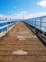 A wood pier leading into the ocean with copy space. An old empty platform or dock terrace on a lake with blue water. Wooden jetty, old bridge or a wharf near a lakehouse getaway retreat during summer