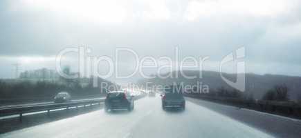 Cars at breaking distance on a highway on a rainy day in Denmark. Motor vehicles driving on a dangerous asphalt road on a cold misty winter day in a picturesque landscape. Safe driving in bad weather