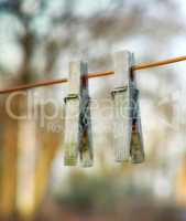 Two wooden washing pegs on a line.Two old wooden clothespins hanging on a washing line in a sunny garden. Old fashioned tools used for hanging freshly cleaned laundry