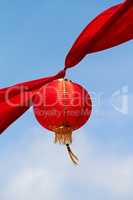 Red Chinese lantern in the air decorating the streets of China. Traditional Asian decor for new year celebrations in beautiful sky background. Creative cultural art hanging high up on a summer day