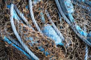 Buoys and a net tangible together as fishing gear or equipment at a harbor. Closeup of blue sea markers and mesh piled, grouped, or gathered together on a boat useful for a background.