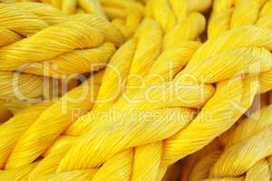 Closeup of a strong and colorful yellow rope. New heavy duty marine ropes on a sailing vessel. Macro of bright yellow color synthetic rope. Texture of twisted or braided polypropylene rope, copyspace