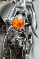 An orange turning light, signal and indicator on a shiny black motorbike. Closeup detailed texture of warning bulb used for road safety, precaution when riding on a highway or street. Safe motorists
