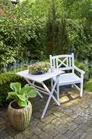 Wooden white garden furniture on a secluded patio outside. High angle view of a cozy area for coffee and reading outdoors. Private location to relax and enjoy alone time in the warm summer weather