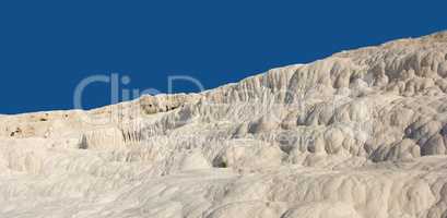 Landscape of the Travertine pools and terraces in Pamukkale Turkey. Desert sand with textured pattern against a blue sky. Tourism holiday destination at rock cotton castle location during hot springs