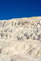 The Travertine pools and terraces in Pamukkale, Turkey. Desert sand with curvy pattern texture against a blue sky. Tourism holiday destination at rock cotton castle location during hot springs
