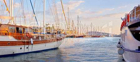 The marine harbor of Bodrum, Turkey. Scenic view of expensive yachts moored in Milta Marina. Closeup of boats and yachts docked at a port or pier during sunset on the water during a warm summer day