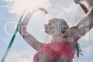 Woman in red bikini using hose to shower on boat after swimming. Woman using a hose to shower on a boat. Young woman showering herself on a boat using a hose