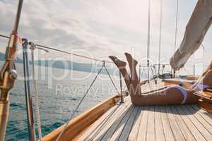 Legs of sexy woman in white bikini lying on boat sunbathing. Woman in white bikini tanning legs on a boat. Sexy legs of woman wearing white bikini sunbathing on a cruise