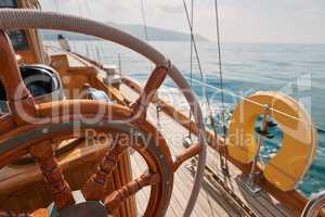 Closeup of wooden steering wheel on empty boat sailing the ocean. Closeup of empty boat deck with rigging cables wooden steering wheel sailing the ocean.