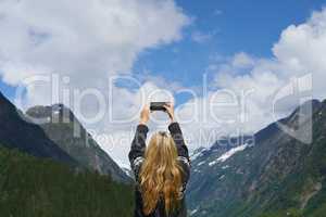 Adventure woman taking photo smart phone of glacial valley landscape on travel exploration for social media