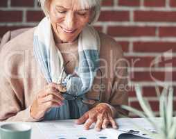Senior woman reading retirement contracts. Mature woman sitting down reading financial paperwork. A happy mature woman holding her glasses reading over legal documents