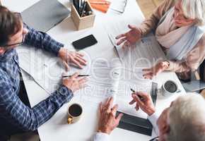 A mature businessman and businesswomen planning contracts with their coworker. A senior couple meeting their banker to discuss and plan their retirement from above. A mature couple signing contracts