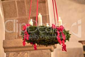Decorative ornament hanging from the roof inside a building. Beautiful candlelight wedding decor indoors. A Christmas design indoors of a church. Red and green adornment creatively beautifying a room