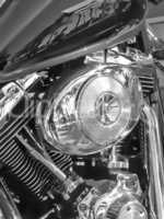 Closeup of metallic motorcycle engine details. A classic, shiny chrome motorbike engine at a motorcycle repair shop. Zoom in on a silver design, black motorbike during annual service at a garage