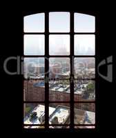 City skyline from an apartment or office window on a bright sunny day. View from inside an empty dark penthouse or hotel room with square glass windows overlooking downtown residential buildings