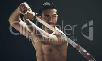 I fight with my heart. a handsome young man standing alone in the studio and posing with a broadsword.