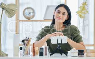 Portrait of beauty blogger smiling while sitting with her smart phone and doing a make-up tutorial. Beautiful young influencer sharing her beauty products and regime