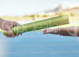 Closeup of two athletes passing a baton during a relay race on a running track. Active fit athlete handing the baton over during a relay race to a team member while running in an sport competition