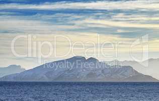 Scenic view of snowcapped mountains along a coast in Bodo, Norway. Expansive natural vista of a lake during sunrise in the morning. Remote, lush vegetation alongside a lake in a European destination