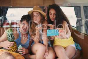 Good friends, great adventures. Shot of a group of young friends taking selfies with a smartphone on a road trip.