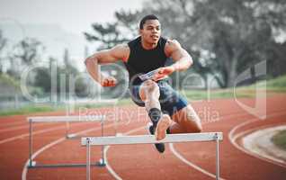 Its important to time your jumps correctly. Full length shot of a handsome young male athlete practicing hurdles on an outdoor track.