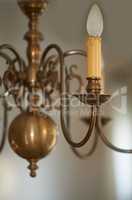 Closeup of a vintage brass chandelier hanging as decoration in a foyer, entrance hall or dinning room during a blackout. Golden candle like lighting decor for a royal victorian style interior design