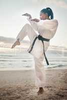 You dont want to mess with her. Shot of a young martial artist practising karate on the beach.