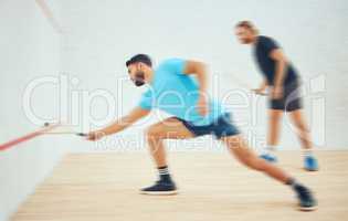 Two athletic squash players playing match during competitive court game. Fit active mixed race and caucasian athlete competing during training challenge in sports centre. Full length with motion blur