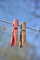 Plastic material decay, crack and discoloration on household objects caused by UV radiation. Closeup details of old pegs on a clothing line outdoors against blurred background with copy space