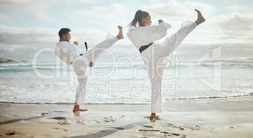 Its all about technique. Full length shot of two young martial artists practicing karate on the beach.