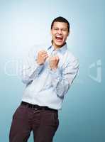 Success is very becoming for a young man. Shot of a young man shouting in joy against a studio background.