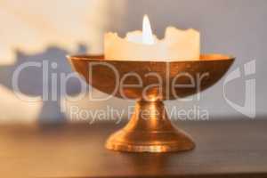 Elegant and decorative lit candle on a table at home. Beautiful house decorations used for aroma, good scent and to brighten up a dark room. Candles represent light, illumination, and purification