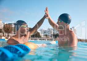 Winners are made in the water. two young men giving each other a high five while going for a swim in an olympic pool.