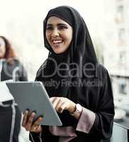 She enjoys working wirelessly. an attractive young businesswoman dressed in Islamic traditional clothing using a tablet on her office balcony.