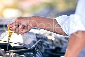 Maybe its the oil. Cropped shot of an unrecognizable man checking under the hood of his car after suffering a vehicle breakdown.