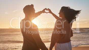 Biracial couple holding their hands together in a heart shape at the beach. Biracial couple holding their hands together in a heart shape at the beach.