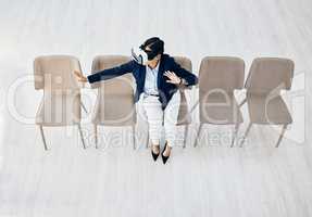 Immersed in a whole new world. High angle shot of a young businesswoman wearing a VR headset while sitting in line in an office.